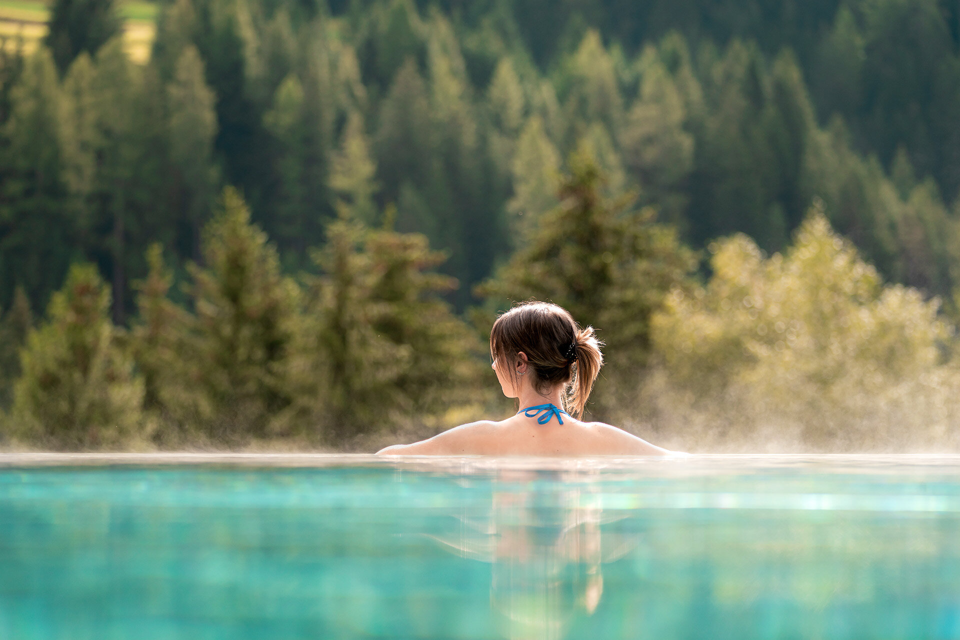 Ragazza di spalle in una piscina esterna con vista sulle Dolomiti in Val di Fassa | © Mattia Rizzi - Archivio Immagini ApT Val di Fassa 