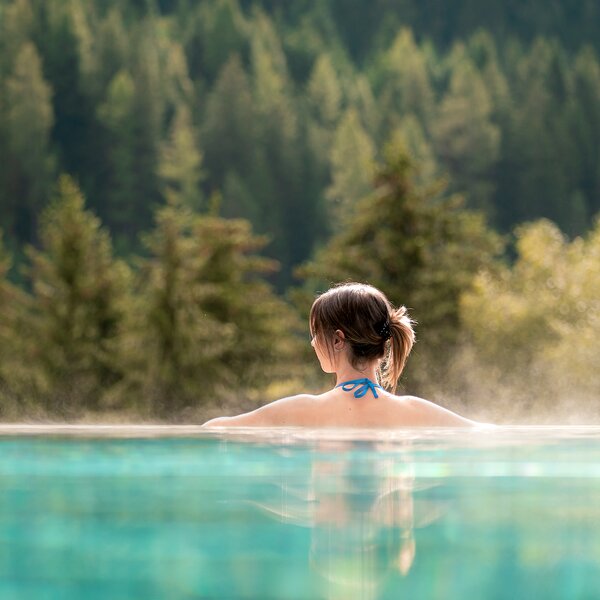 Ragazza di spalle in una piscina esterna con vista sulle Dolomiti in Val di Fassa | © Mattia Rizzi - Archivio Immagini ApT Val di Fassa 