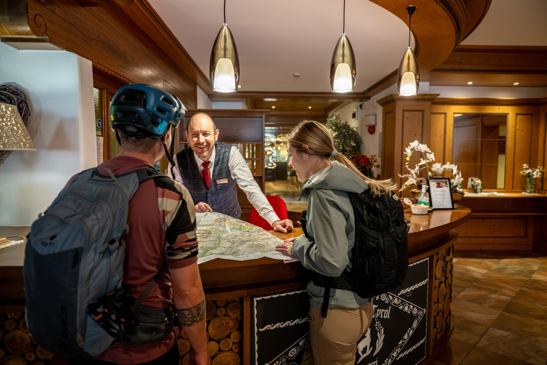 Un receptionist consiglia due biker su quali percorsi seguire, all'interno di un hotel | © Andrea Costa - Archivio immagini ApT Val di Fassa