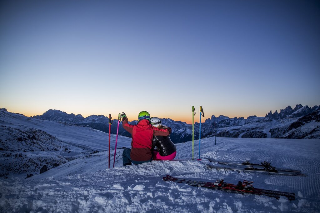 Coppia sugli sci che guarda l'alba sulle Dolomiti in Val di Fassa