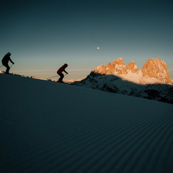 Coppia scia all'alba in Val di Fassa con vista sul Sassolungo | © Archivio immagini ApT Val di Fassa - Federico Modica