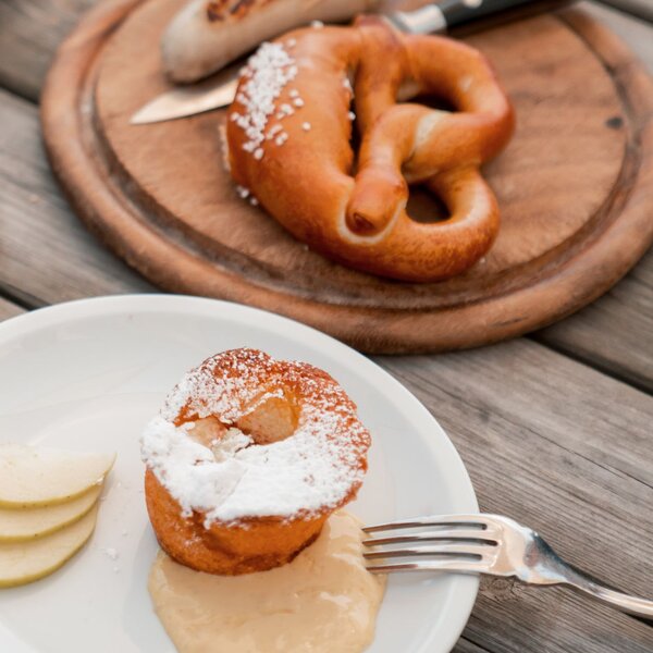 Tavolo apparecchiato per la merenda con Bretzeln, bratwurst e tortino di mele | © Archivio immagini ApT Val di Fassa - Mattia Rizzi
