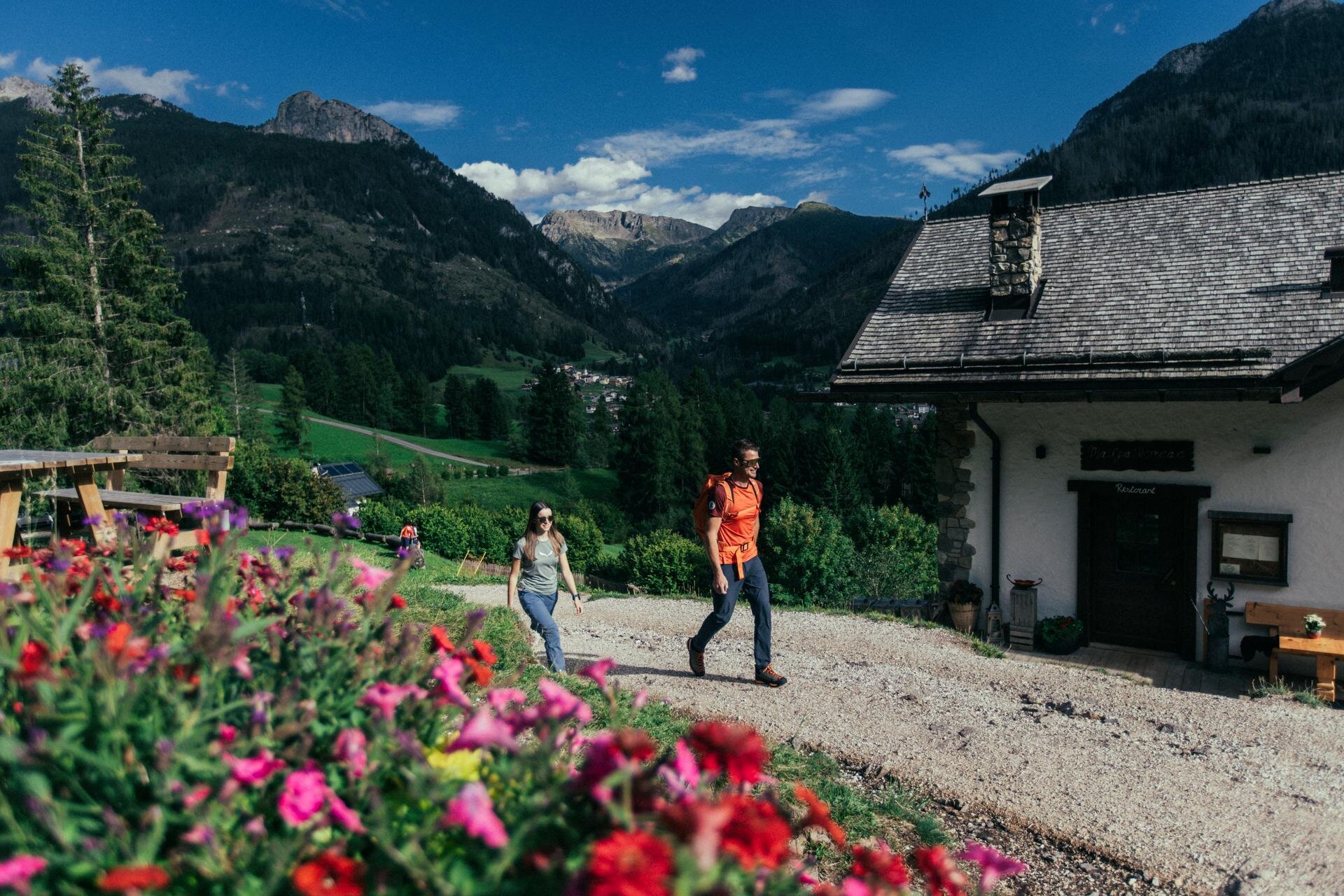 Coppia cammina fra i prati e le case di Moena in Val di Fassa | © Archivio Immagini ApT Val di Fassa - Federico Modica