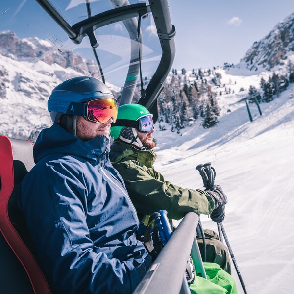 Persone che sorridono mentre salgono in quota in seggiovia in Val di Fassa | © Patricia Ramirez - Archivio Immagini ApT Val di Fassa