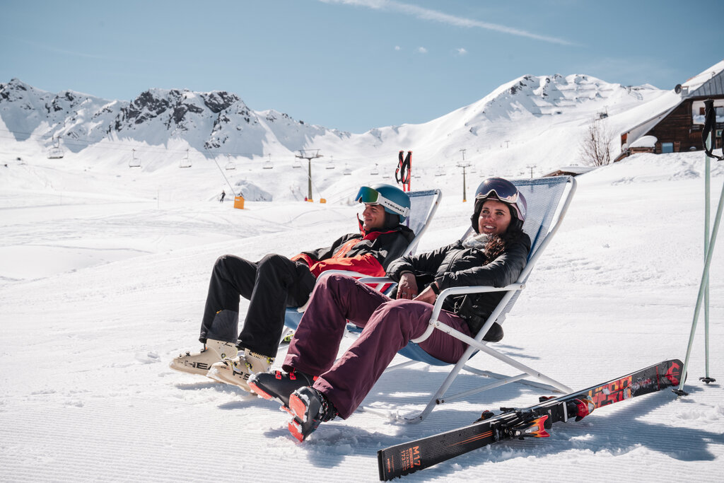 Coppia di sciatori si riposano su sdraio nella skiarea Ciampac