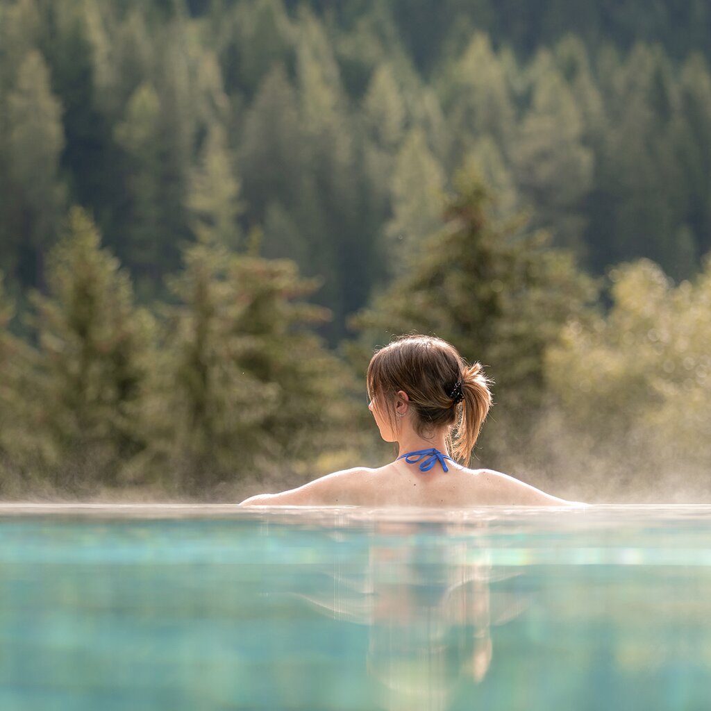 Ragazza di spalle in una piscina esterna con vista sulle Dolomiti in Val di Fassa | © Mattia Rizzi - Archivio Immagini ApT Val di Fassa 