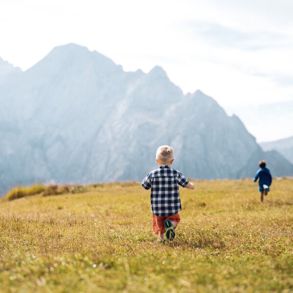 Bambini che corrono su un prato sulle Dolomiti in Val di Fassa | © Mattia Rizzi  - Archivio Immagini ApT Val di Fassa