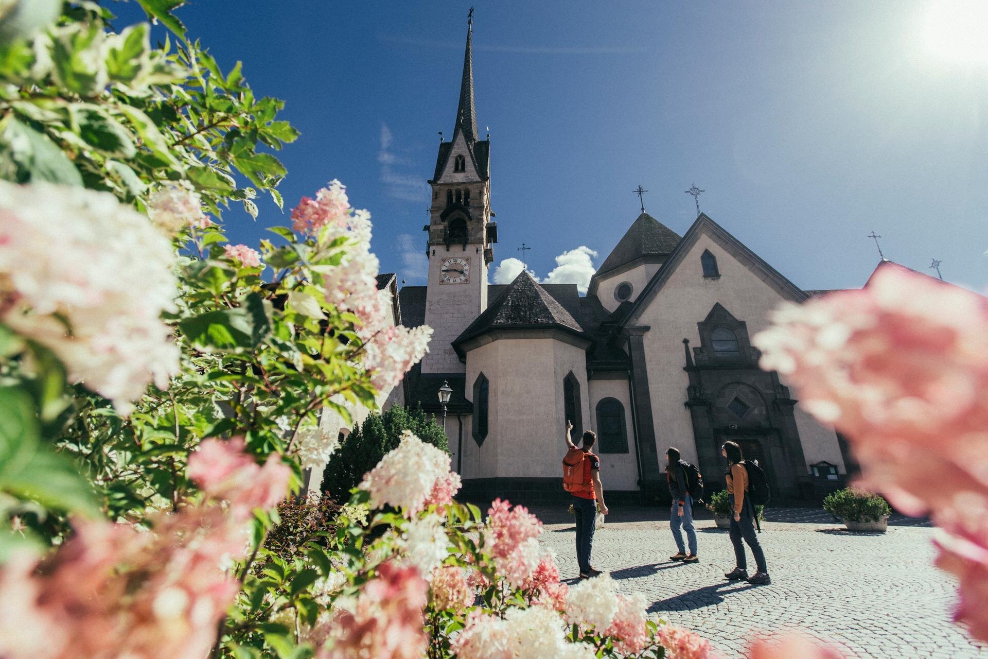 La chiesa principale di Moena con in primo piano un cespuglio fiorito | © Archivio immagini ApT Val di Fassa - Federico Modica