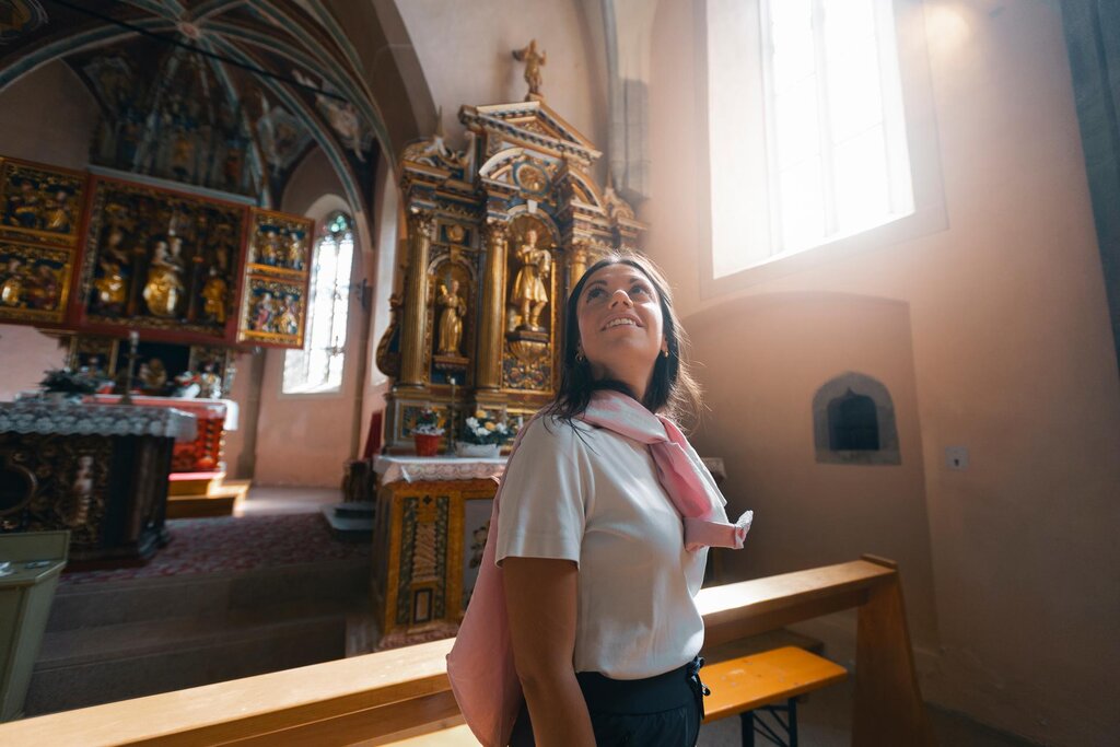 Una ragazza ammira le decorazioni lignee della chiesa di Santa Giuliana a Vigo di Fassa