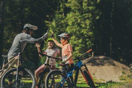 Ragazzi che battono il cinque all'istruttore di MTB dopo un corso in Val di Fassa