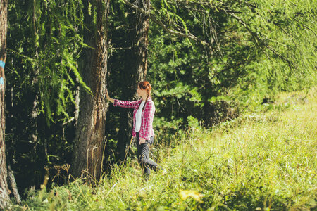 Ragazza che tocca un albero per beneficiare delle energie della natura in Val di Fassa