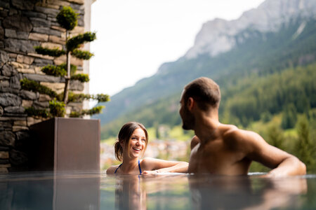 Persone in una piscina esterna con vista sulle Dolomiti in un hotel in Val di Fassa