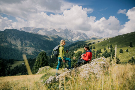 Persone che si riposano su un prato durante un trekking sulle Dolomiti in Val di Fassa