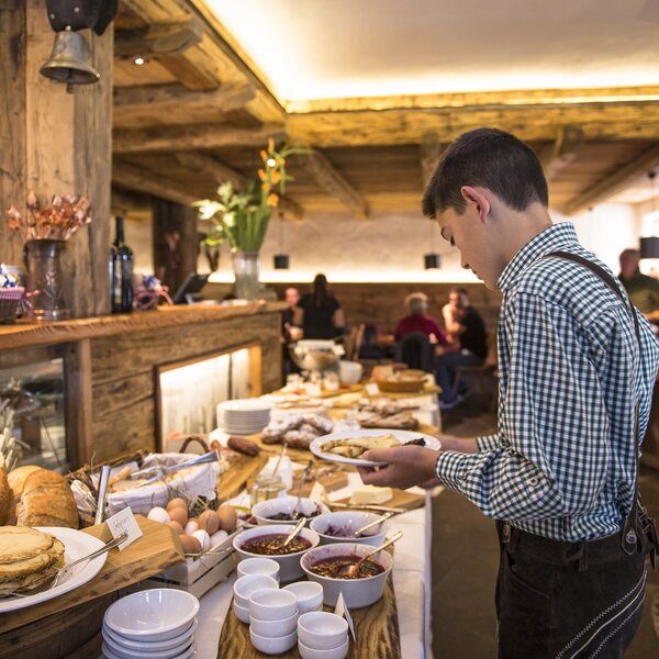 Ragazzo in abiti locali mentre si serve al buffet di un agriturismo | © Andrea Costa - Archivio Immagini ApT Val di Fassa