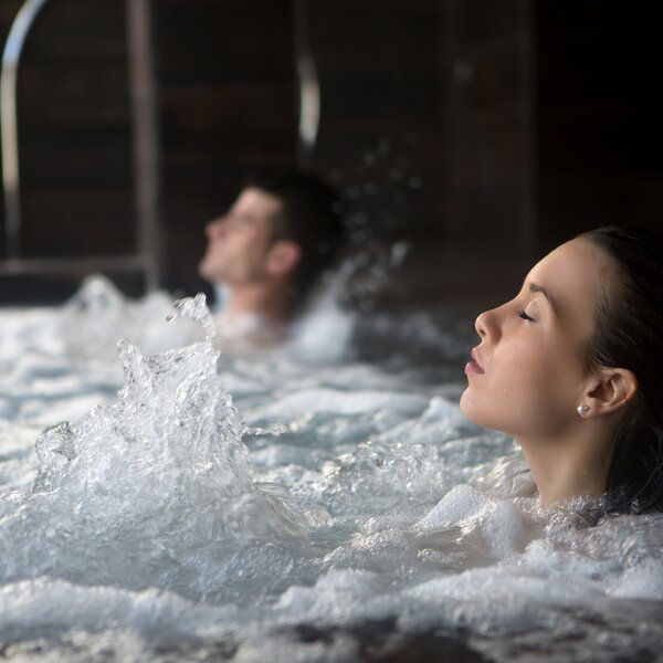 Coppia che si rilassa nelle acque di una piscina idromassaggioo | © Archivio Immagini ApT Val di Fassa