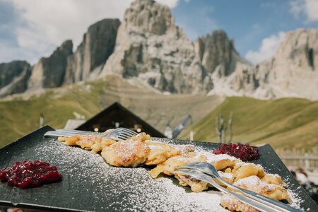 Piatto tipico di un dolce ladino in Val di Fassa, sullo sfondo le Dolomiti